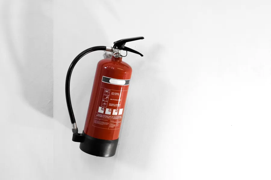 Extincteur accroché sur un mur blanc.