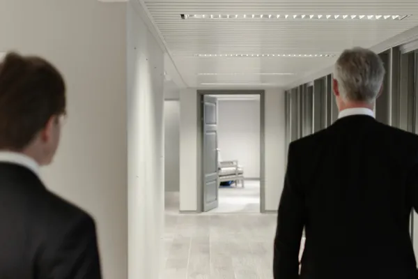 Deux hommes, habillé de manière très professionnelles, se dirigent vers une salle.
