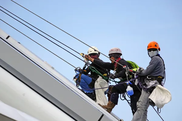 3 homme travaillent sur la façade d'un bâtiment.