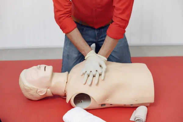 Homme effectuant un massage cardiaque sur un mannequin.